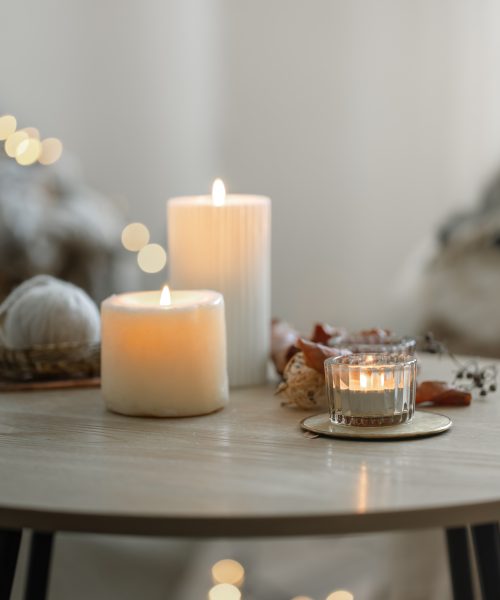 Cozy home composition with candles on blurred bokeh background. Beautiful burning candles in the interior of a room in a Scandinavian style.